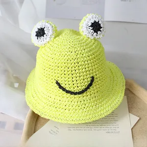 Détail d'un chapeau de paille jaune avec yeux de grenouille et sourire pour protection solaire