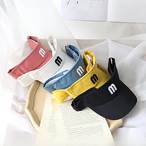 Detail of five colorful kids' sun visors with letter m embroidery on a soft tray