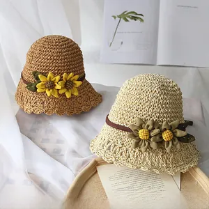Détail de chapeaux de paille tressés avec fleurs de tournesol et bords ondulés ajourés