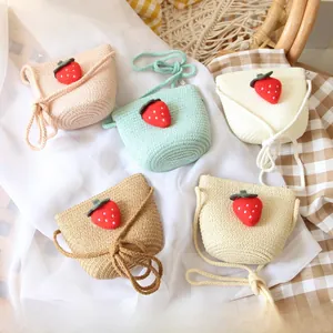 Flat lay of colorful handmade strawberry straw crossbody bags for kids in five pastel colors