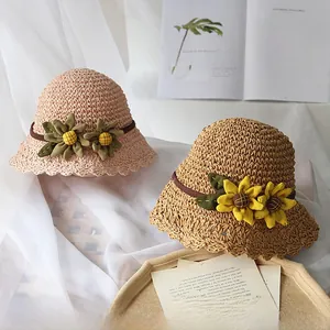 Détail de chapeaux en paille tissés main avec fleurs de tournesol en rose et kaki