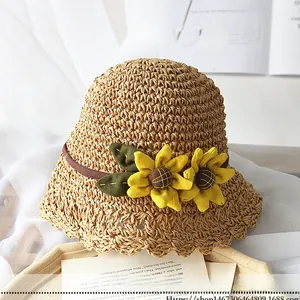 Détail d'un chapeau de paille tressé avec tournesols en tissu et bord ondulé pour la plage
