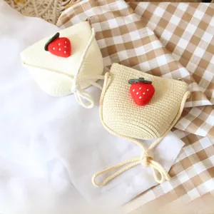 Close-up of children's woven straw bags with cute strawberry felt decoration and zipper