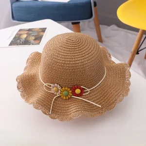 Close-up of handwoven straw hat showing delicate floral ornaments and scalloped edges