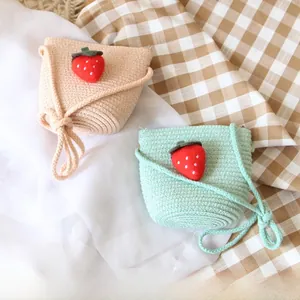 Detail of beige and mint green straw woven bags for kids with 3D strawberry patches