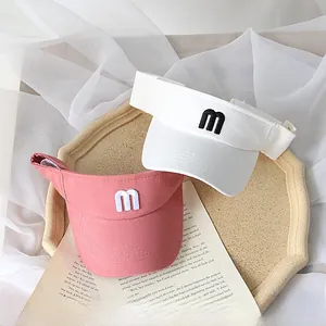 Detailed view of white and pink kids sun visors with embroidered 'm' logo on tray