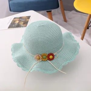 Detailed texture of mint green woven straw hat with delicate fabric floral decorations