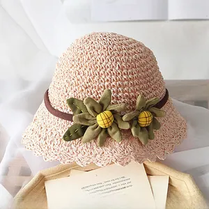 Détail du bord ondulé et de la fleur en tissu vert sur un chapeau de soleil en paille