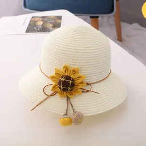 Detail of cream straw hat with yellow sunflower decor and plush pompom drawstring