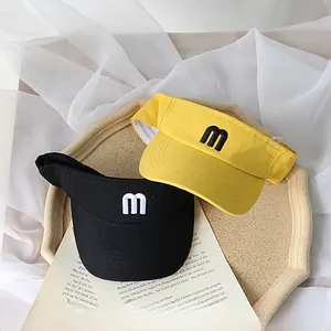 Detail view of children's sun visor hats with 'm' embroidery on a decorative tray
