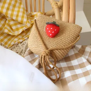 Close-up of handmade straw bag for kids featuring a red felt strawberry decoration