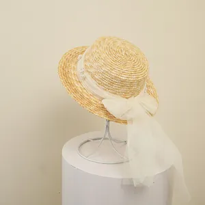 Detail of children's straw boater hat featuring a large lace bow and white pearl accents