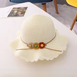 Detailed view of woven straw hat with wavy brim and colorful floral accents for kids