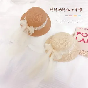 Top view of two straw hats featuring delicate white tulle ribbons and pearl accents