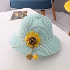 Detail of light blue woven straw sun hat for girls with sunflower and pompom tassels