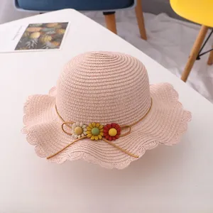 Detail of pink straw sun hat for girls with woven texture and colorful daisy flowers