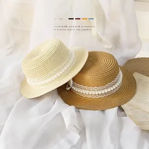 Detail of woven straw sun hats with delicate lace trim and imitation pearl embellishments