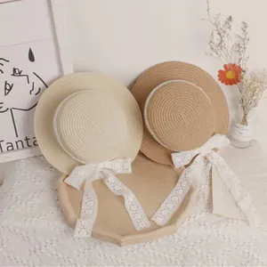 Close-up of woven straw sun hats with delicate white lace ribbons and bow details