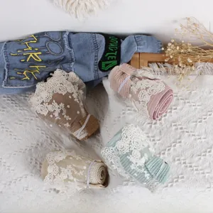 Detail of four colorful knit leg warmers with delicate white floral lace edges