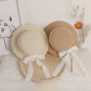 Detail of flat-top straw hats with white hollow lace ribbons in light beige and natural brown