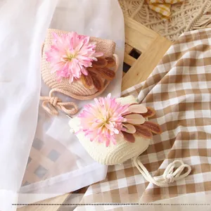 Close-up of mini handmade straw bags for girls with pink floral deco and cotton straps