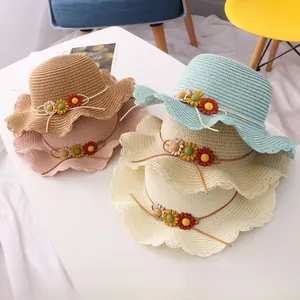 Detail of four colorful woven straw hats for kids featuring decorative 3D floral accents
