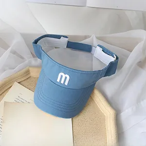 Detail of blue sun visor for kids featuring white letter m embroidery and adjustable strap
