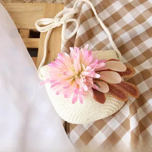 Detail of girls' woven straw bag with pink flower decoration and white rope strap