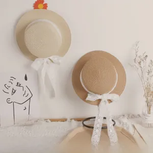 Detail of children's straw sun hats with white lace ribbons and floral accents