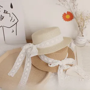 Detail of stacked cream and khaki straw sun hats with white lace ribbons and bows