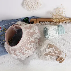Detailed flat lay of lace-trimmed straw sun visors in pink, blue and khaki colors