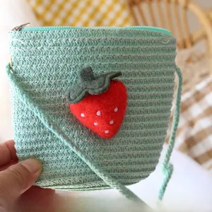 Detail of mint green woven straw bag for kids with red strawberry applique and zipper closure