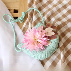 Detail of light green straw woven crossbody bag with pink flower for young girls