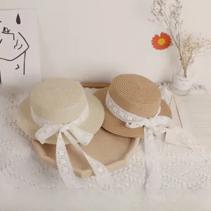 Detailed view of handmade straw hats with delicate white lace trim and ribbons