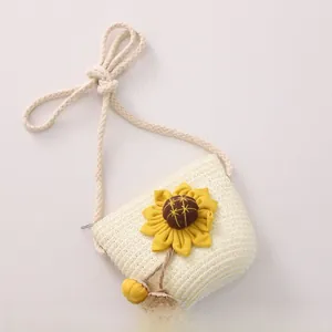 Detail of woven straw crossbody bag for girls featuring a yellow sunflower and cord strap