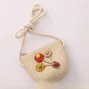 Detailed macro view of a child's straw crossbody bag with floral accents and ladybug
