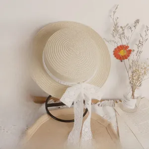 Close-up of a woven straw sun hat with detailed white lace ribbon and bow decoration