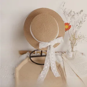 Detail view of woven straw sun hat with white lace ribbon tie on a display stand
