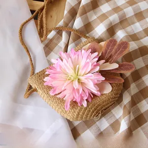 Detail of a handmade straw bag with pink flower decoration and woven shoulder strap