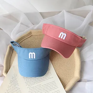 Blue and pink kids sun visors with embroidered m letter on a vintage tray background