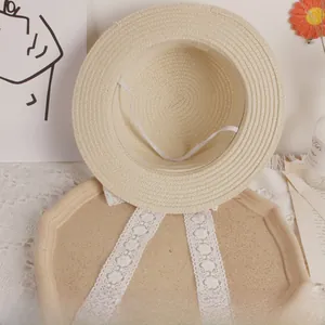 Detail of beige straw hat featuring elegant white lace ribbons and woven texture
