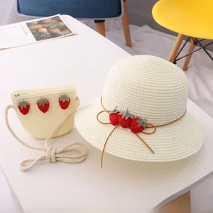 Détail du chapeau de paille crème et du sac à bandoulière assorti avec motifs de fraises