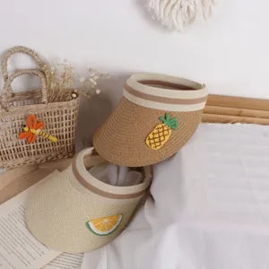 Detail of straw sun visors featuring embroidered pineapple and orange fruit patches