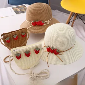 Détail du motif fraise sur chapeaux en paille et sacs tressés assortis pour petites filles
