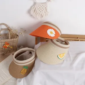 Detail of woven straw sun hats for kids featuring cute fruit and flower embroidery patches
