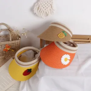 Detail view of woven straw sun visors with fruit decorations for kids summer wear