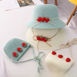 Vue à plat de chapeaux de paille et sacs fraise en bleu clair et crème pour filles
