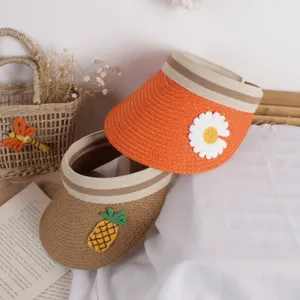 Detail view of woven straw sun hats for kids with daisy and pineapple embroidery