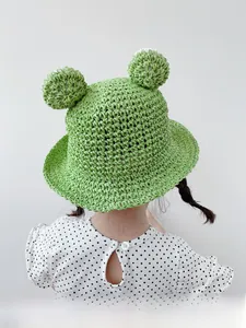 Rear view of a kids crochet frog hat with green pompoms and breathable mesh weave