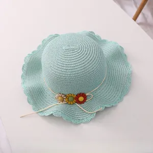 Close-up of mint green straw sun hat with woven scalloped brim and flower details